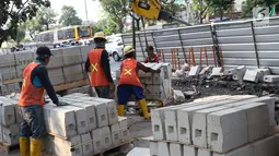 Aktivitas pekerja menyelesaikan proyek revitalisasi trotoar di Jalan Salemba Raya, Jakarta, Jumat (6/9/2019). Proyek revitalisasi trotoar dengan anggaran Rp 75 miliar ini ditargetkan rampung pada Desember mendatang. (Liputan6.com/Helmi Fithriansyah)