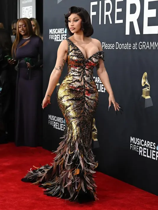 Gaun ini dihiasi dengan manik-manik, payet, dan bulu yang menciptakan efek menyerupai motif harimau dalam kombinasi warna emas dan hitam. [@iamcardib].