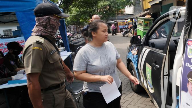 Seorang perempuan yang tidak mengenakan masker bersiap menaiki mobil Satpol PP di Tangerang, Kamis (14/5/2020). Pemkot Tangerang melakukan tindakan bagi pelanggar PSBB dengan membawa mereka ke kantor Kecamatan Karawaci Baru untuk dilakukan rapid test Covid-19. (Liputan6.com/Angga Yuniar)