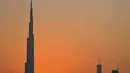 Pemandangan matahari terbenam di belakang Burj Khalifa dan gedung-gedung bertingkat lainnya, di Dubai, Uni Emirat Arab pada Sabtu (12/9/2020). (Photo by Karim SAHIB / AFP)