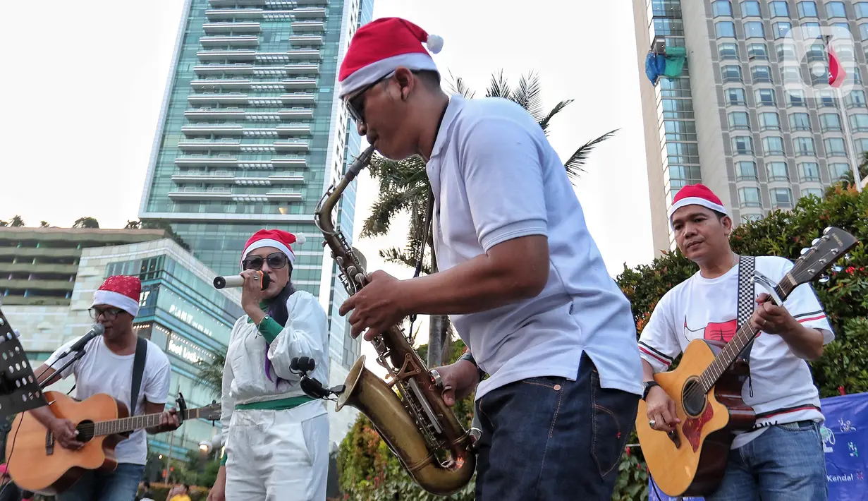 Musisi mengelar pertunjukan musik bernuansa Natal di jalur Pedestrian Bundaran HI, Jakarta Pusat, Selasa (20/12/2022). Pergelaran musik bernuansa Natal tersebut sebagai bentuk pertunjukan untuk menghibur warga yang melintas di Kawasan itu. (Liputan6.com/Angga Yuniar)