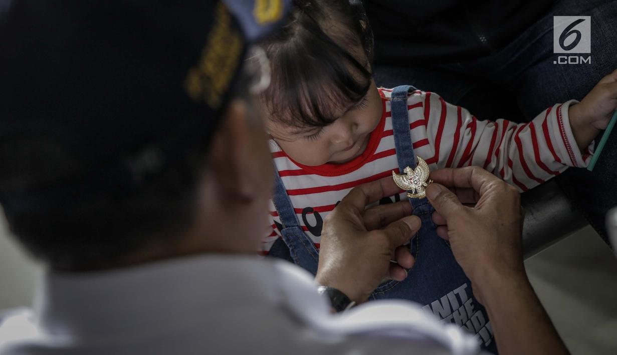 Petugas PT KAI Daop 1 memberikan pin garuda kepada penumpang di Stasiun Gambir, Jakarta, Kamis (1/6). Dalam rangka memperingati HUT Pancasila PT KAI Daop 1 memberikan pin dan bendera merah putih kepada penumpang kereta api. (Liputan6.com/Faizal Fanani)