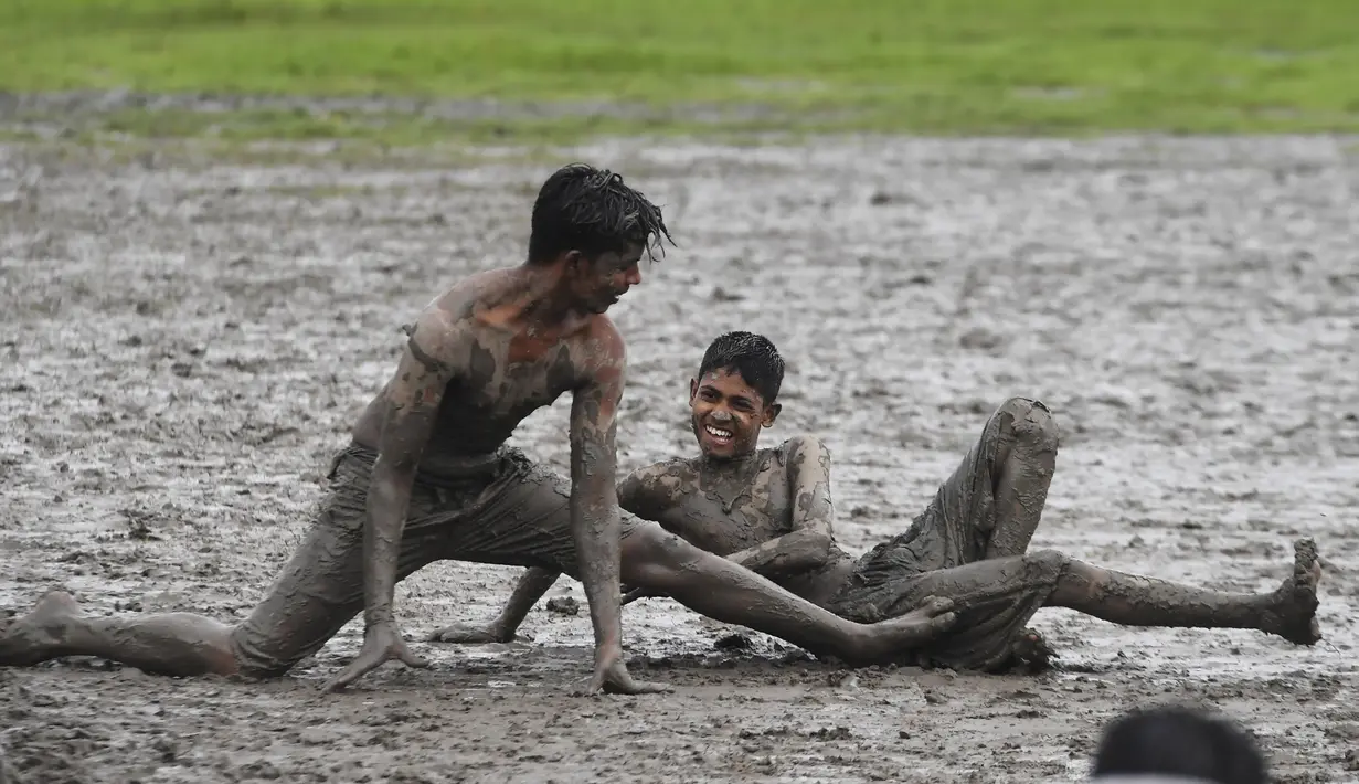Anak-anak memainkan permainan Kabaddi di sebuah lahan yang digenangi air di Kolkata (8/9/2019).  Olahraga ini awalnya merupakan permainan untuk mempersiapkan tentara. (AFP Photo/Dibyangshu Sarkar)