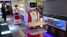 Leah Hu (kiri) menunjukkan penggunaan robot pengganti pelayan sebagai bagian dari uji coba langkah-langkah aturan jaga jarak di restoran keluarga Royal Palace, Belanda, 27 Mei 2020. Robot ini bertugas menyapa pelanggan, menyajikan makanan dan minuman dan mengembalikan alat makan. (AP/Peter Dejong)