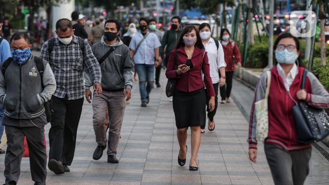 Sejumlah orang berjalan di trotoar pada saat jam pulang kantor di Kawasan Sudirman, Jakarta, Senin (8/6/2020). Aktivitas perkantoran dimulai kembali pada pekan kedua penerapan Pembatasan Sosial Berskala Besar (PSBB) transisi pandemi COVID-19. (Liputan6.com/Johan Tallo)