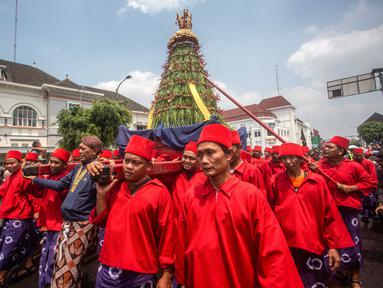 Para pengawal keraton yang dikenal secara lokal sebagai ‘abdi dalem’ membawa gunungan, sebuah persembahan berbentuk gunung dari hasil panen, selama upacara Grebeg, tradisi suci Keraton Yogyakarta pada 5 September 2025. (DEVI RAHMAN/AFP)