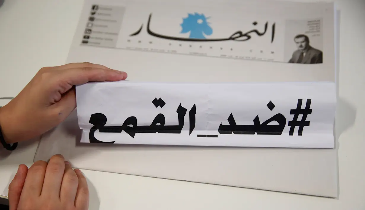 Seorang wartawan surat kabar harian An-Nahar, memegang kertas dengan kata-kata Arab yang berbunyi: "Terhadap penindasan," pada salinan surat kabar dengan halaman kosong tanpa berita, di kantor An-Nahar, Beirut, Kamis (11/10). (AP/Hussein Malla)