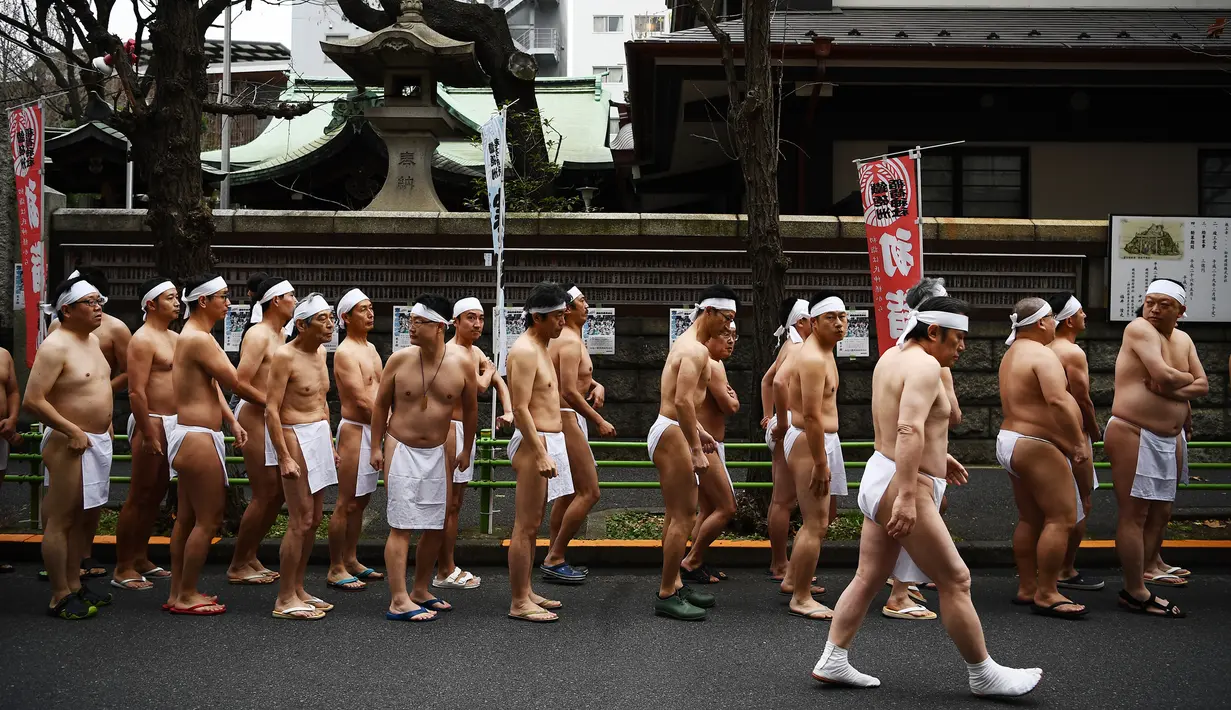 Orang-orang percaya Shinto dari Kuil Teppozu Inari mengelilingi kuil untuk melakukan pemanasan sebelum mandi di air dingin untuk memurnikan jiwa dan tubuh mereka selama ritual Tahun Baru di Tokyo (12/1/2020).  (AFP/Charly Triballeau)