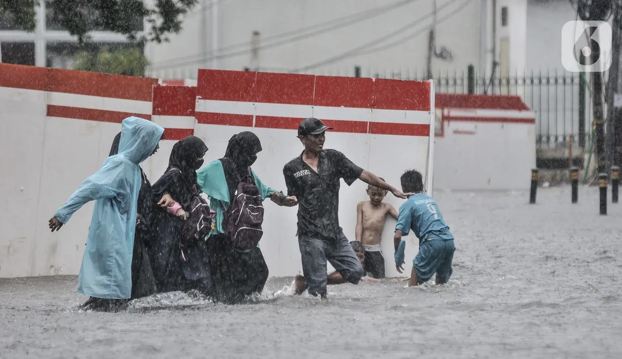 Warga membantu pengguna kereta menerobos banjir di Jalan Abdullah Syafei, Tebet, Jakarta, Kamis (18/2/2021). Hujan deras yang mengguyur sejak pagi menyebabkan aliran Kali Tebet meluap hingga merendam Jalan Abdullah Syafei dengan ketinggian mencapai sepaha orang dewasa. (merdeka.com/Iqbal S Nugroho)