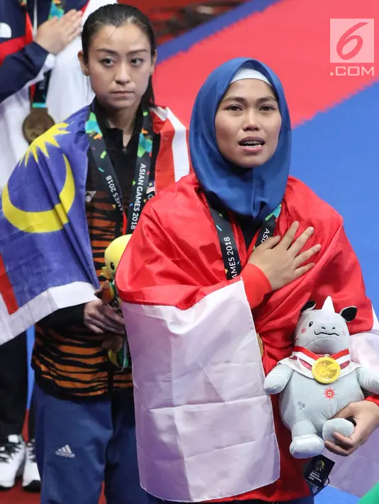Atlet Taekwondo putri Indonesia, Defia Rosmaniar saat di podium kemenangan Final Women Individual Poomsae di JCC, Jakarta, Minggu (19/8). Defia Rosmaniar meraih emas usai menumbangkan Salahshouri Marjan dari Iran. (Liputan6.com/Helmi Fithriansyah)