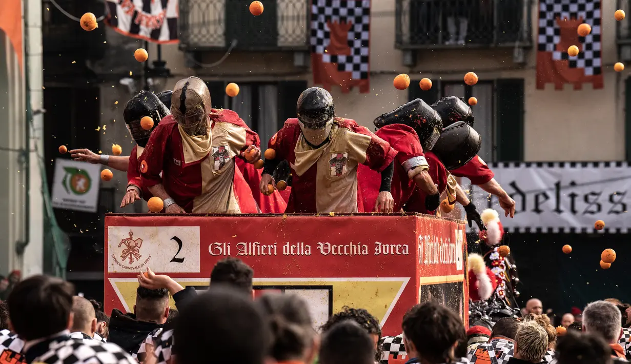 Peserta dan pasukan penjaga saling melemparkan jeruk sebagai bagian dari tradisi "perang jeruk" selama Karnaval Ivrea di Turin, Italia, Minggu (3/3). Festival ini biasa dilaksanakan di bulan Februari setiap tahunnya selama tiga hari (MARCO BERTORELLO/AFP)