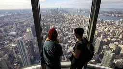 Pengunjung menikmati pemandangan Kota Manhattan dari ruangan observatorium di lantai 102 Gedung Empire State yang baru direnovasi di New York (10/10/2019). Dibuka untuk umum pada 12 Oktober, ruang observatorium ini berjarak 1.250 kaki di atas permukaan jalan. (AFP Photo/Drew Angerer)