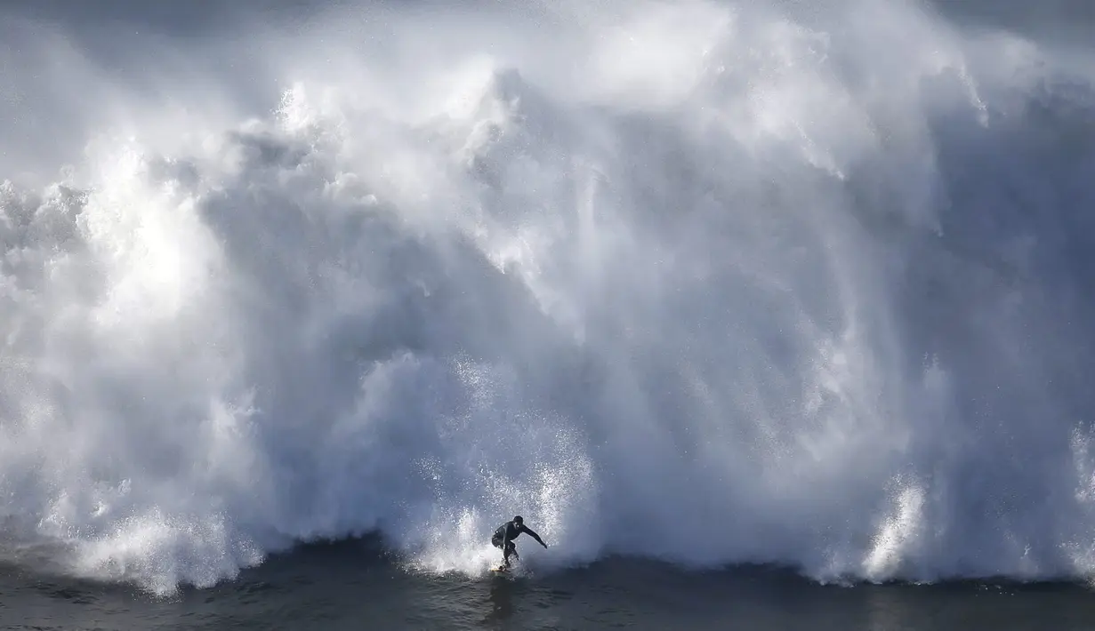 Seorang atlet meluncur di depan gelombang raksasa di Pantai Praia do Norte, Nazare, Portugal, (29/11/2015). (Reuters/Rafael Marchante)
