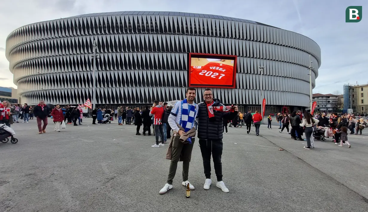 Dua fans dari Real Sociedad dan Athletic Bilbao berpose di halaman Stadion San Mames, Bilbao, Spanyol menjelang laga lanjutan Liga Spanyol 2023/2024 antara Athletic Bilbao dan Real Sociedad, 13 Januari 2024. (Bola.com/Yus Mei Sawitri)