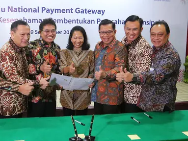 Menteri BUMN Rini Soemarno (tengah) bersama Gubernur BI Agus Martowardojo dan sejumlah Dirut Bank BUMN tengah memegang naskah MoU sinergi pembentukan perusahaan prinsipal di Jakarta, Jumat (9/9). (Liputan6.com/Angga Yuniar)