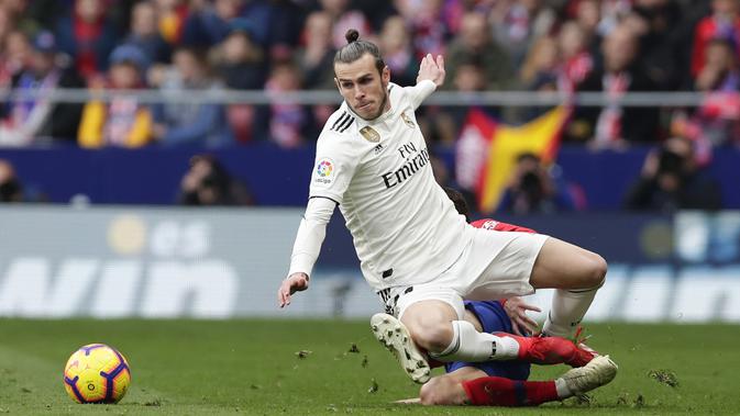 Penyerang Real Madrid, Gareth Bale, terjatuh saat berebut bola dengan pemain Atletico Madrid, Santiago Arias, pada laga La Liga di Stadion Wanda Metropolitano, Sabtu (9/2). Real Madrid menang 3-1 atas Atletico Madrid. (AP/Manu Fernandez)