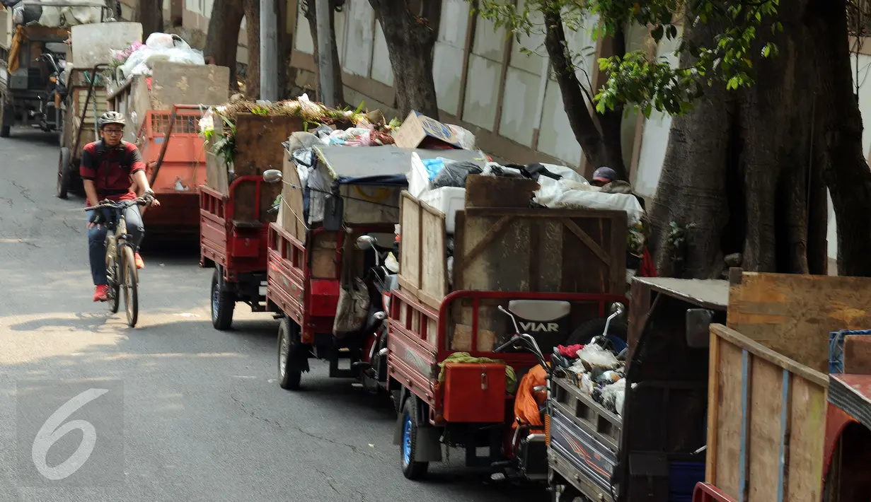 Warga melintas di sisi motor gerobak sampah di Tempat Pembuangan Sampah Sementara Kalibata, Jakarta, Rabu (4/11/2015). Penumpukan sampah terkait aksi pemblokadean jalan menuju TPST Bantar Gebang. (Liputan6.com/Helmi Fithriansyah)