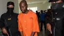 Warga Negara Tanzania, Abdul Rachman Azman dikawal petugas sebelum konferensi pers di Kantor Pelayanan Bea Cukai Bandara Ngurah Rai, Bali, Selasa (12/2). Abdul ditangkap karena menyelundupkan methamphetamine 1,13 kg di dalam perutnya (Sonny TUMBELAKA/AFP)