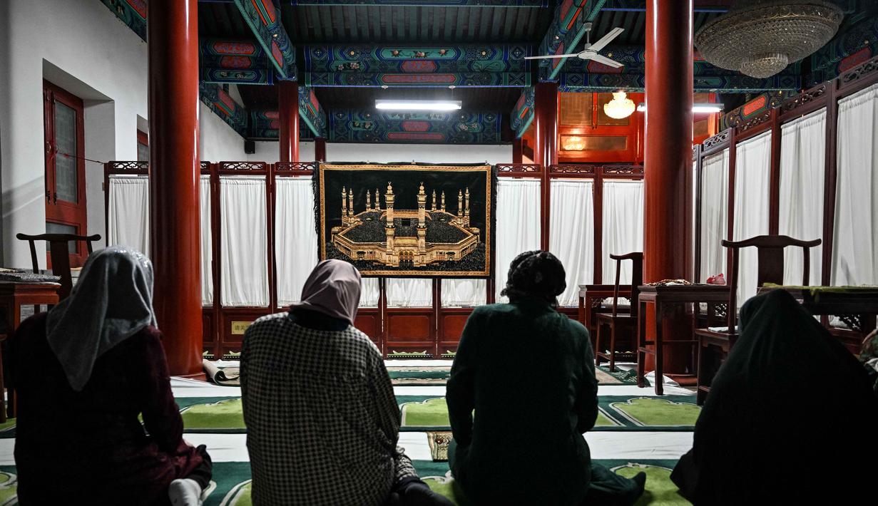Identitas etnis Hui didefinisikan oleh keyakinan mereka terhadap Islam yang berpadu harmonis dengan elemen budaya Tionghoa Han yang dominan. Tampak dalam foto, perempuan Muslim etnis Hui Tiongkok melaksanakan salat di sebuah masjid selama minggu terakhir bulan suci Ramadhan di Beijing pada 17 Maret 2026. (Adek BERRY/AFP)