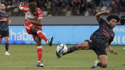 Striker Bayern Munchen, Kingsley Coman (kiri) melepaskan tendangan yang berusaha diblok bek Manchester City, Rico Lewis pada laga pramusim 2023/2024 bertajuk Audi Football Summit di Stadion Nasional Tokyo, Jepang, Rabu (26/7/2023) malam WIB. (AFP/Kazuhiro Nogi)