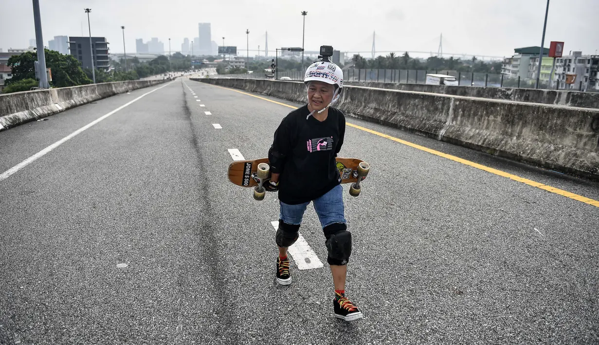 Longboarder dan penderita kanker Nongluck Chairuettichai, juga dikenal sebagai Jeab, berjalan di jalan raya yang belum selesai selama sesi latihan di Bangkok pada 9 September 2020. Kegiatan ini dilakukan sebagai jalan pemulihan dari kanker payudara yang dideritanya. (Lillian SUWANRUMPHA/AFP)