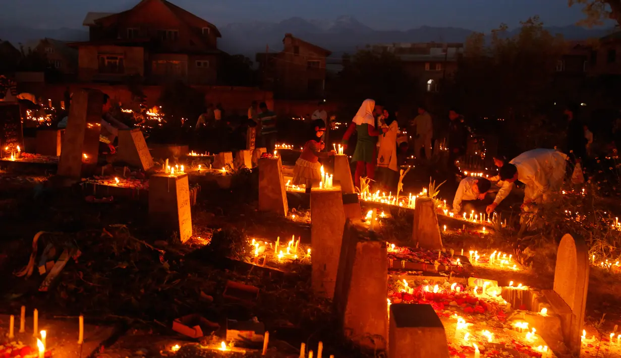 Sejumlah umat Syiah Kashmir menyalakan lilin di pemakaman keluarga dan saudara mereka saat memperingati Shab-e-Barat di pinggiran Srinagar, Kashmir (11/5). Dalam peringatan tersebut mereka berdoa dan meminta ampunan. (AP Photo / Mukhtar Khan)