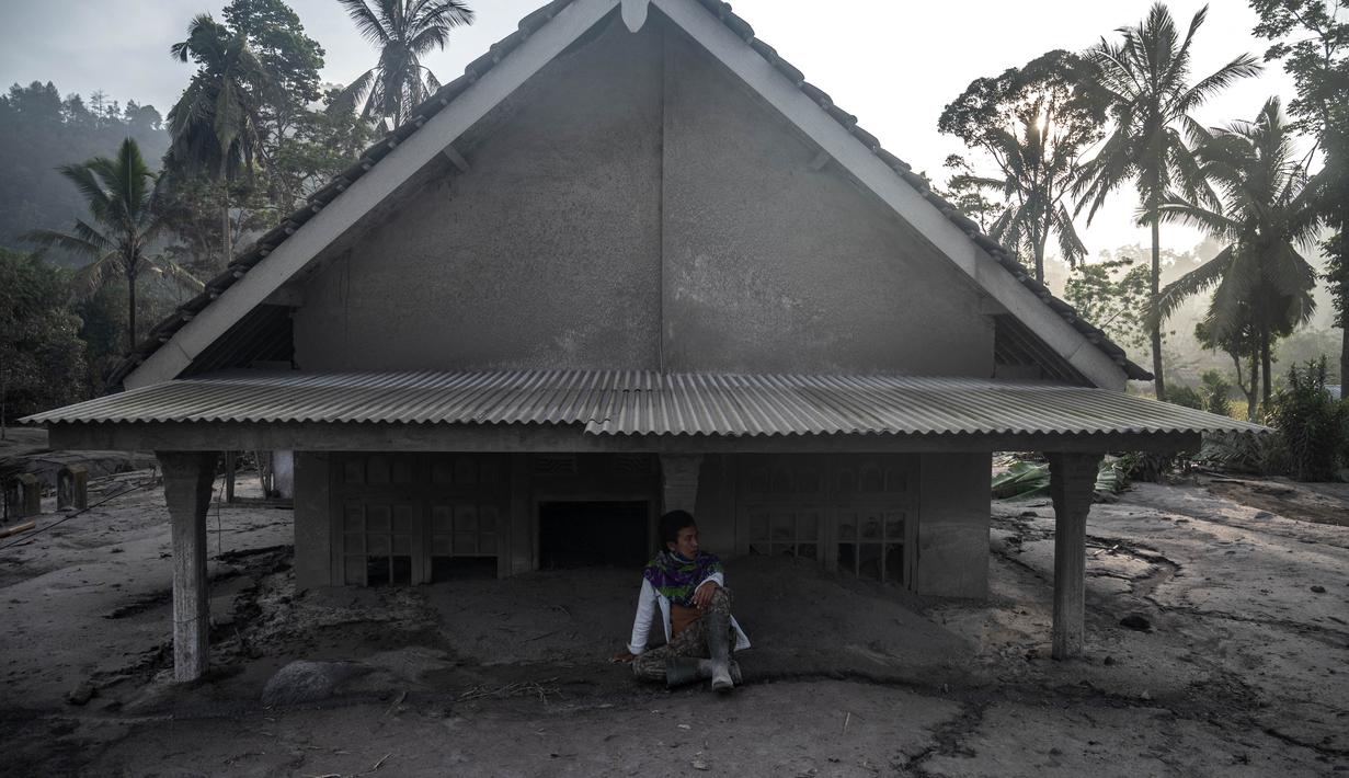 Seorang pria duduk di depan sebuah rumah yang terendam lumpur setelah letusan gunung berapi oleh Gunung Semeru di desa Kajar Kuning di Lumajang (5/12/2022). Gunung Semeru meletus pada tanggal 4 Desember memuntahkan awan abu panas setinggi satu mil dan sungai lava di sisinya sambil memicu evakuasi hampir 2.000 orang tepat satu tahun setelah letusan besar terakhirnya menewaskan puluhan orang. (AFP/Juni Kriswanto)
