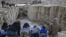 Warga Israel menyaksikan banjir bandang terjadi menyusul hujan lebat di gurun Negev di sebelah timur kota Dimona Israel pada 26 Desember 2022. Hujan lebat mengguyur Israel pada hari Senin (26/12) membanjiri jalan-jalan kota, memicu banjir bandang di dasar sungai gurun yang kering dan membasahi daerah pedesaan karena suhu turun ke level terendah musim ini. (AFP/Menahem Kahana)