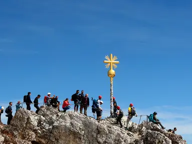 Orang-orang mengantre untuk mencapai puncak salib di puncak gunung tertinggi Jerman, Zugspitze, dekat Garmisch-Partenkirchen, Jerman pada 19 Agustus 2020. Setiap tahunnya gunung dengan ketinggian 2.962 meter tersebut membuat sekitar setengah juta pengunjung terpesona. (AP Photo/Matthias Schrader)