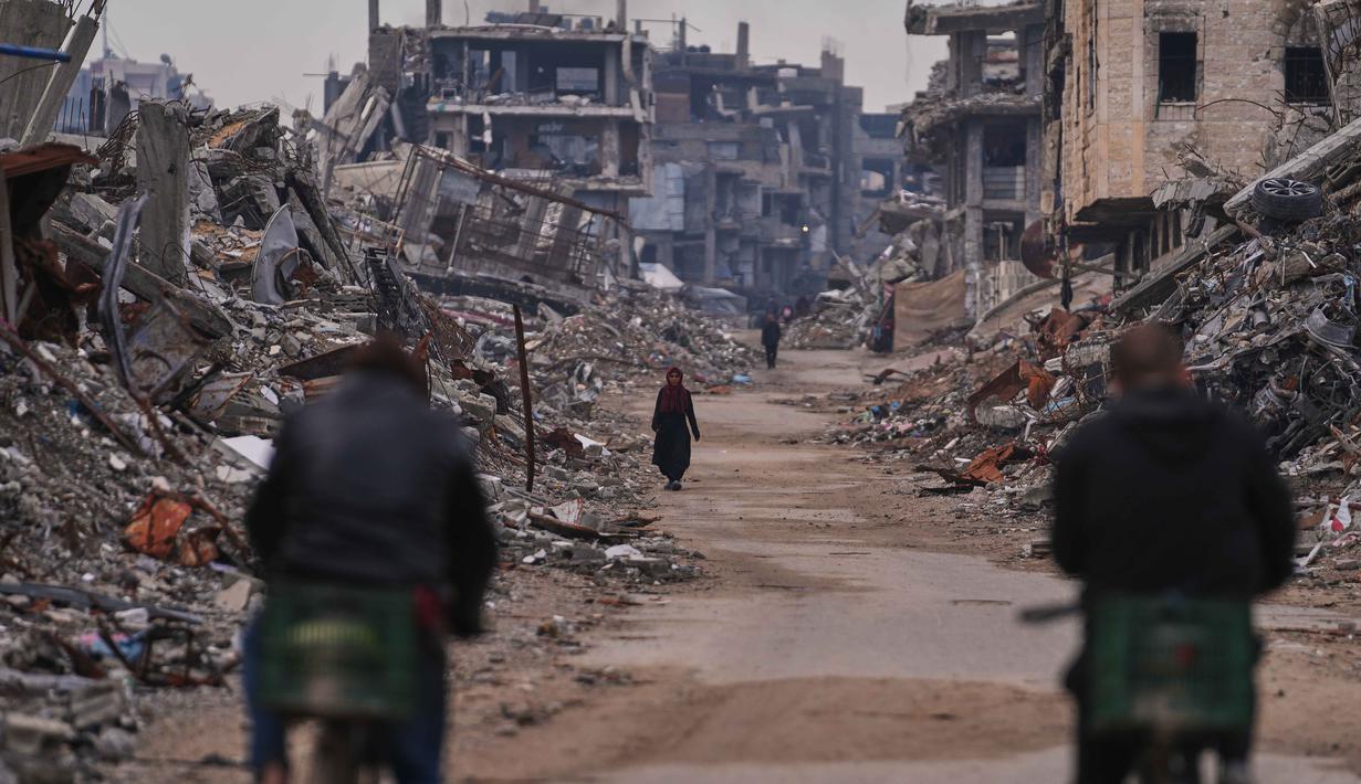 Sedikitnya 235.000 warga Palestina di Jalur Gaza terdampak krisis akibat cuaca ekstrem yang memperparah dampak perang berkepanjangan di wilayah tersebut. Tampak dalam foto, seorang wanita Palestina berjalan di sepanjang jalan yang dikelilingi bangunan-bangunan yang hancur akibat serangan udara dan darat Israel di lingkungan Sheikh Radwan, Kota Gaza, Selasa, 30 Desember 2025. (AP Photo/Abdel Kareem Hana)