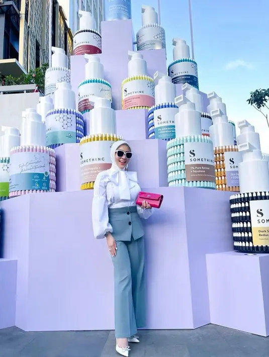 Perempuan yang baru genap 40 tahun itu terlihat mengenakan white blouse dengan detail pita di bagian depan, dipadukan dengan high waist pants warna abu-abu. (Instagram/princessyahrini).