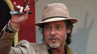 Brad Pitt menyapa penggemar saat menghadiri acara karpet merah untuk film "Once Upon a Time In Hollywood" di Mexico City (12/8/2019). Aktor 55 tahun itu tampil necis dalam setelan jas krem, sepatu boot, dan kemeja mustard. (AP Photo/Marco Ugarte)