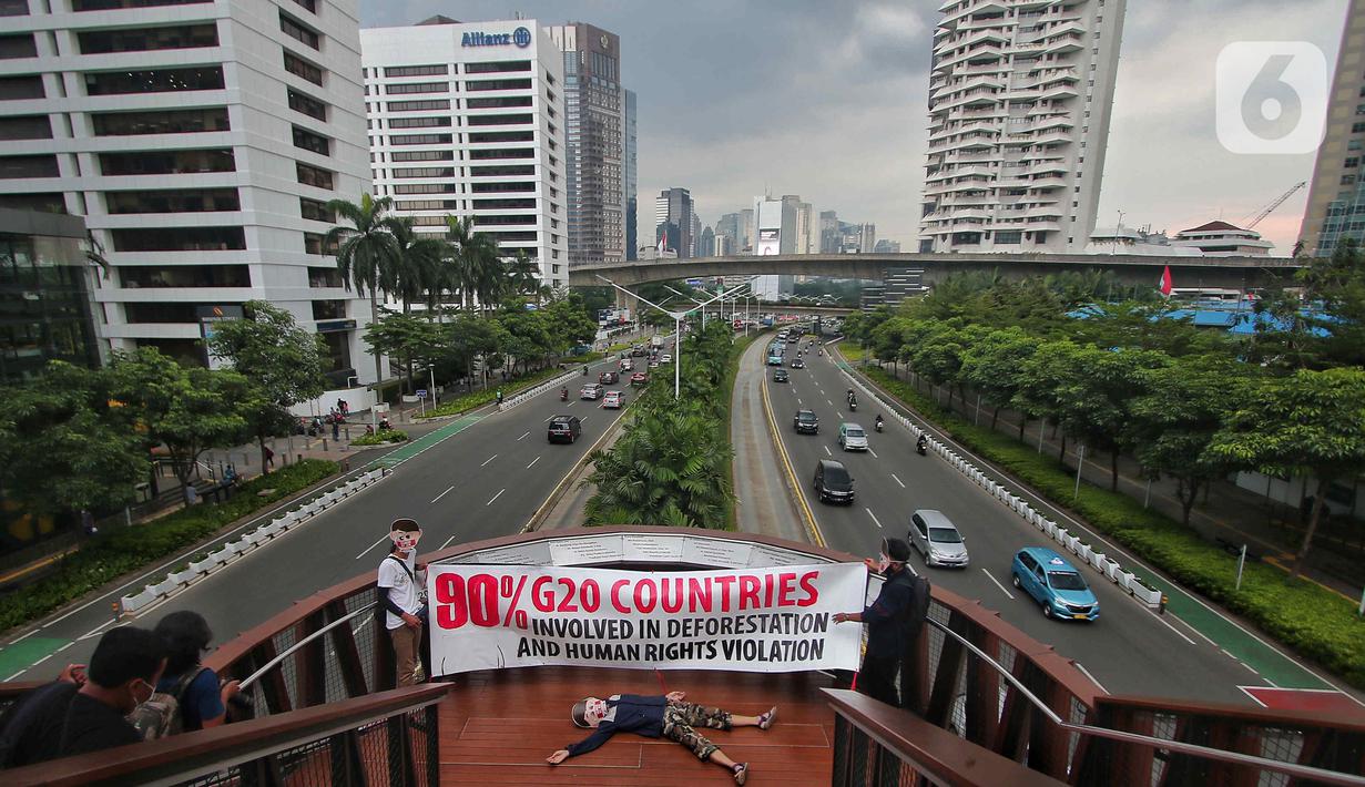 Sejumlah aktivis yang tergabung dalam Extintion Rebellion (XR) dan Walhi Jakarta melakukan aksi di JPO Pinisi, Jalan Jenderal Sudirman, Jakarta, Senin (14/11/2022). Aksi tersebut dilakukan untuk menyerukan kepada para pemimpin agar menghentikan “pencucian hijau” dan praktik ekonomi “business-as-usual” yang secara sistematis memperburuk krisis iklim dan mendorong umat manusia pada kehancuran ekologis & kepunahan massal. Negara-negara G20 turut menyumbang atas 80 persen emisi karbon dunia dan 60 persen populasi penduduk bumi. (Liputan6.com/Angga Yuniar)