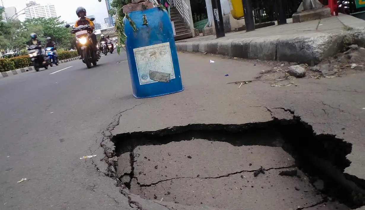 Sebuah rambu darurat diletakkan warga untuk mencegah terjadinya kecelakaan akibat amblasnya sebagian ruas jalan di depan Wisma Bakrie, Jakarta, (12/8/2014). (Liputan6.com/Faizal Fanani)