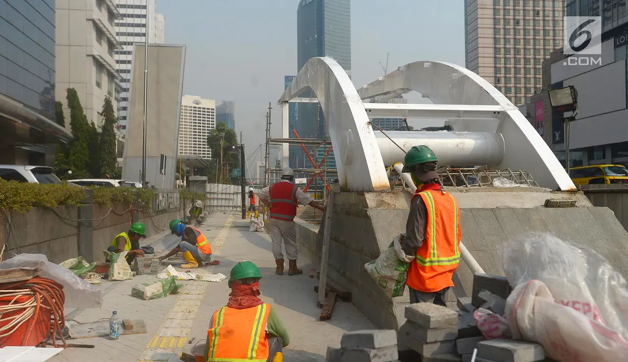 Pekerja menyelesaikan proyek pembangunan trotoar di Jalan MH Thamrin,Jakarta,Kamis (19/7). Pengecatan trotoar di Jalan Sudirman - MH Thamrin dimulai pada 18 Juli - 12 Agustus 2018. (Merdeka.com/Imam Buhori)