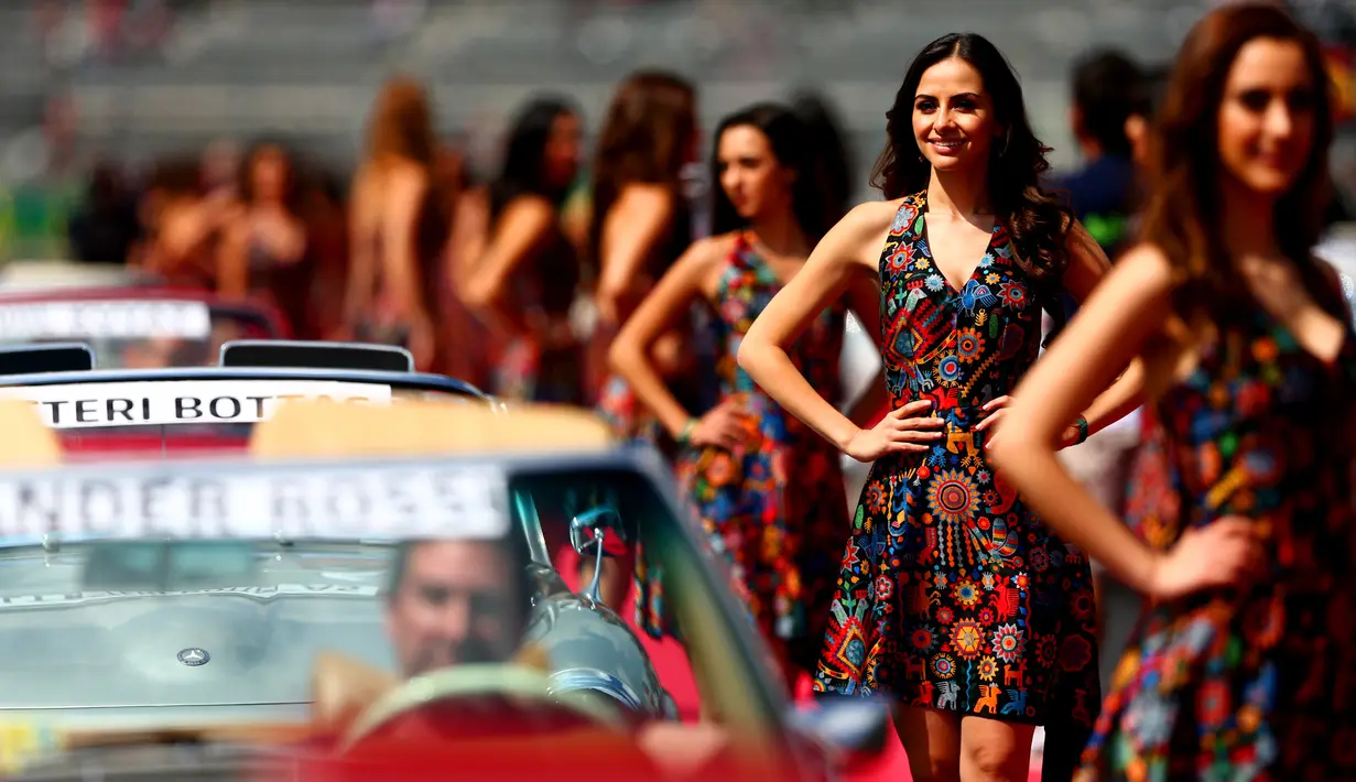 Gadis Grid atau Grid Girls berpose di samping mobil saat parade Grand Prix Formula 1 di Autodromo Hermanos Rodriguez, Meksiko (1/11/2015). Grid Girls akan dihapus saat seri pertama F1 di Melbourne, Australia Maret 2018. (Clive Mason / Getty Images / AFP
