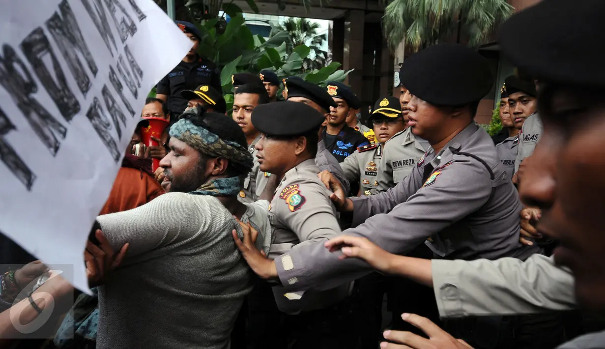 Massa yang tergabung dalam Aliansi Mahasiswa Papua dan FRI-West Papua terlibat saling dorong dengan polisi saat berunjuk rasa di depan kantor PT Freeport di Jakarta, Jumat (7/4). Mereka menuntut penutupan PT Freeport. (Liputan6.com/Helmi Fithriansyah)