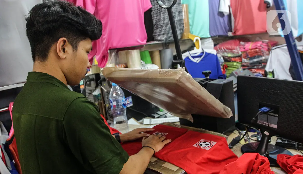 Pedagang menyablon jersey timnas sepak bola peserta Piala Dunia Qatar 2022 di salah satu kios Blok B Pasar Tanah Abang, Jakarta, Kamis (24/11/2022). Menurut pedagang, permintaan jersey timnas meningkat dikarenakan Piala Dunia Qatar 2022 yang dimulai sejak 20 November 2022. (Liputan6.com/Johan Tallo)