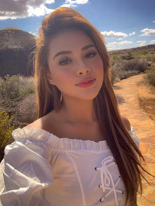Aurel terlihat anggun dan feminin dengan atasan off shoulder berwarna putih berlatar belakang pemandangan indah. Gaya rambut coklatnya banyak dinilai cocok bagi remaja berusia 22 tahun tersebut. (Liputan6.com/IG/@aurelie.hermansyah)