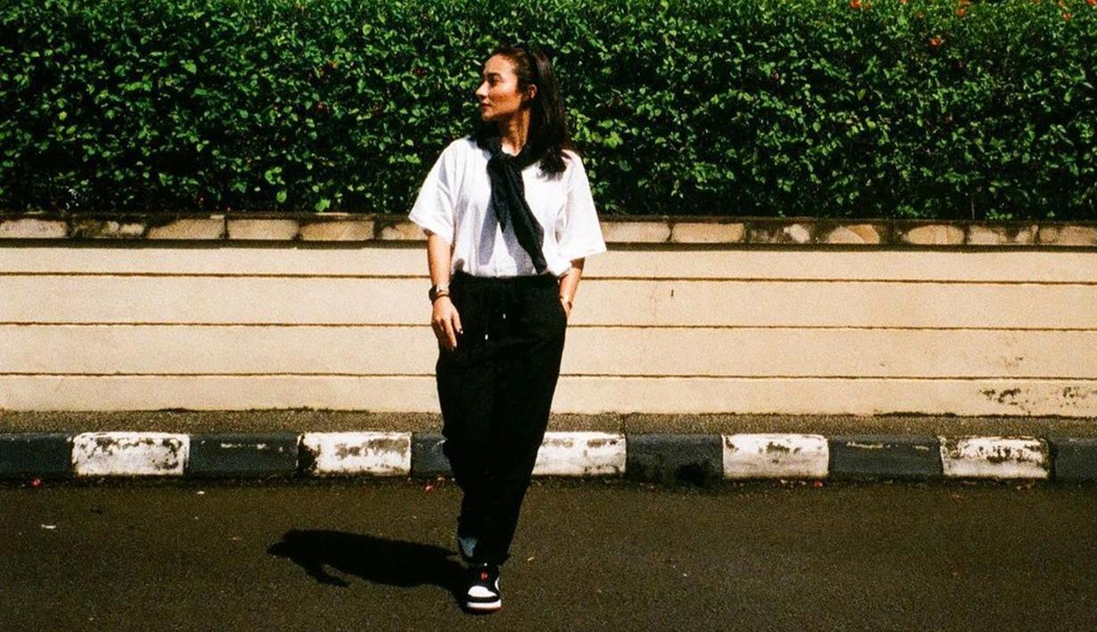 Tampil dengan kaus putih oversize serta celana hitam dan sneakers menjadi salah satu gaya OOTD yang terbilang kasual namun tetap stylish. Dirinya juga memilih untuk mengikat sweater hitam di pundak untuk menunjang detail penampilannya. (Liputan6.com/IG/@naonomnom)