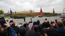 Warga menonton dan memotret saat rudal balistik RS-24 Yars Rusia melintas melewati Kremlin setelah parade militer Hari Kemenangan di Moskow, Rusia, Minggu (9/5/2021). Parade militer ini untuk memperingati 76 tahun berakhirnya Perang Dunia II di Eropa. (AP Photo/Alexander Zemlianichenko Jr.)