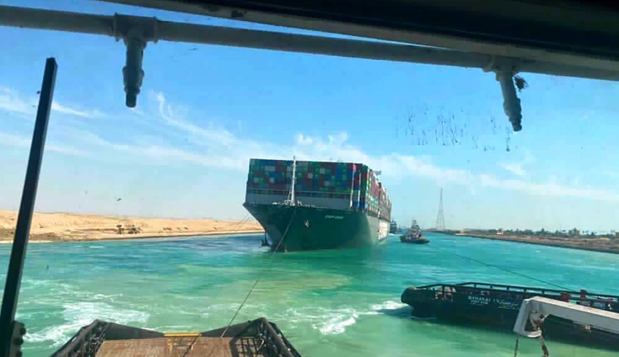 Kapal kargo Ever Given ditarik oleh salah satu kapal tunda di Terusan Suez, Mesir, Senin (29/3/2021). Kapal penarik membunyikan klakson mereka sebagai perayaan saat Ever Given sepanjang 400m (1.300 kaki) dicabut pada Senin 29 Maret dengan bantuan kapal keruk. (Suez Canal Authority via AP)