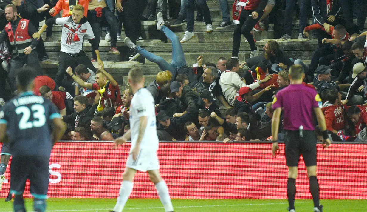 Suporter Lille terjatuh saat pembatas tribun roboh pada laga Ligue 1 Prancis antara Amiens melawan Lille LOSC  di Licorne stadium, Amiens, (30/9/2017). Laga tersebut akhirnya ditunda. (AFP/Francois Lo Presti)