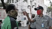 Petugas memeriksa suhu tubuh pengunjung kompleks wisata Kota Tua, Jakarta, Selasa (2/6/2020). Jelang berakhirnya PSBB di Jakarta, pengelola Kota Tua menyiapkan protokol kesehatan new normal bagi pengunjung. (merdeka.com/Iqbal S. Nugroho)