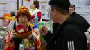 Didominasi warna merah dan emas, dekorasi khas perayaan Tahun Baru Imlek melambangkan keberuntungan, kemakmuran, dan pengusir energi negatif. Tampak dalam foto, seorang pekerja mengenakan kostum dewa keberuntungan untuk menarik pelanggan ke kiosnya saat bazar menyambut Tahun Baru Imlek di Beijing, China, Minggu 1 Februari 2026. (AP Photo/Andy Wong)