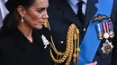 Kate Middleton bersama Pangeran William berjalan mengikuti prosesi persemayaman Ratu Elizabeth II di Westminster Hall di London (14/9/2022). Bros yang dikenakan Kate ini dulu dimiliki oleh Ratu Elizabeth II, sebelum diberikan kepada istri Pangeran William tersebut.  Dalam situs The Court Jeweller, sang ratu pernah menggunakan bros tersebut dalam kunjungan ke Seoul, Korea Selatan pada 1999. (AFP/Ben Stansall)