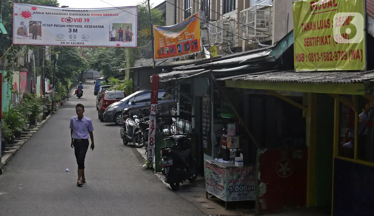 Warga melintasi spanduk zona merah kawasan RW 04 Kelurahan kalibata, Jakarta, Selasa (9/2/2021). Pemerintah mulai menerapkan PPKM skala mikro mulai 9-22 Februari 2021 untuk provinsi yakni DKI Jakarta, Jawa Barat, Banten, Jawa Tengah, Yogyakarta, Jawa Timur, dan Bali. (Liputan6.com/Herman Zakharia)