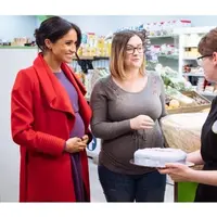 Meghan Markle mengenakan mantel merah untuk membalut gaun berwarna ungu yang memperlihatkan perut hamilnya saat kunjungan ke Birkenhead. (dok. Instagram @kensingtonroyal/Dinny Mutiah)