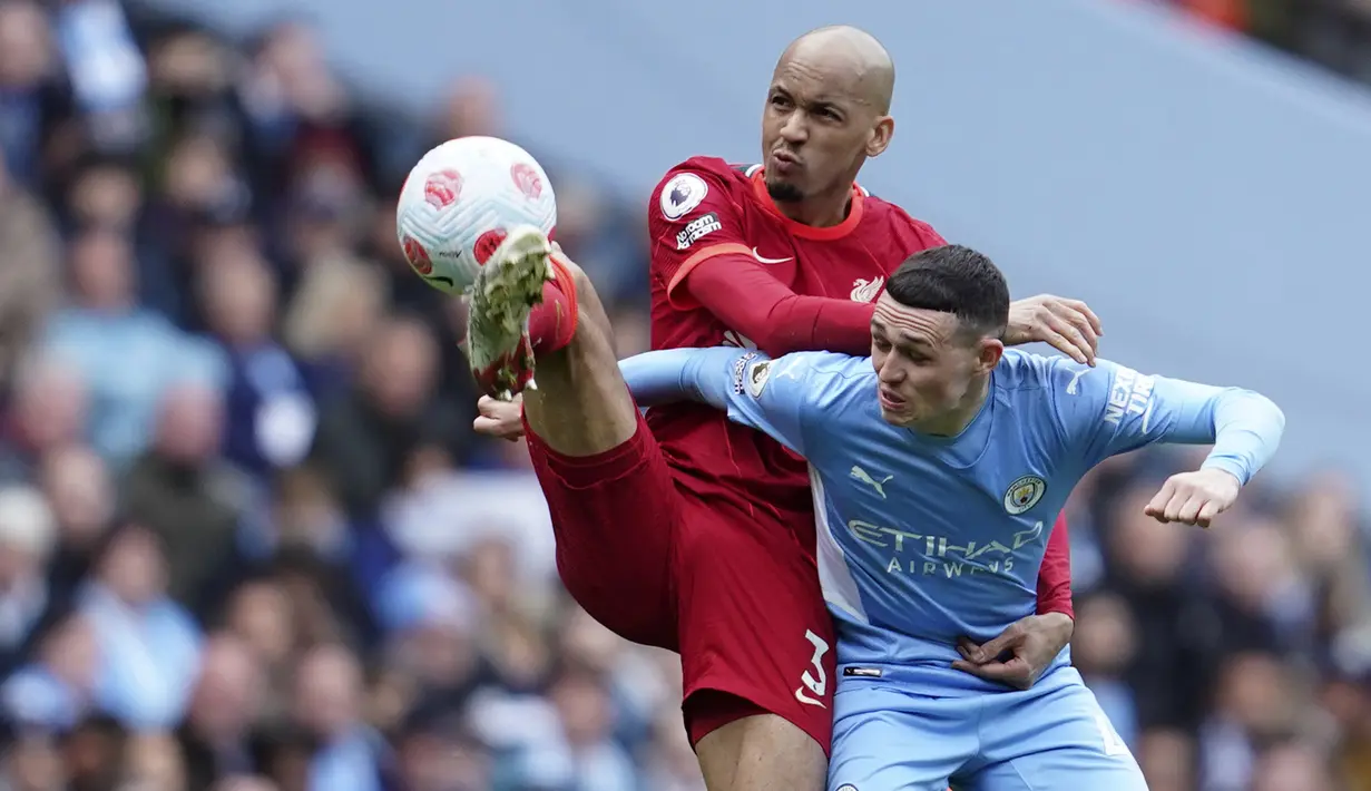 Pemain Liverpool Fabinho (kiri) berduel memperebutkan bola dengan pemain Manchester City Phil Foden pada pertandingan sepak bola Liga Inggris di Etihad Stadium, Manchester, Inggris, 10 April 2022. Laga berakhir imbang 2-2. (AP Photo/Jon Super)