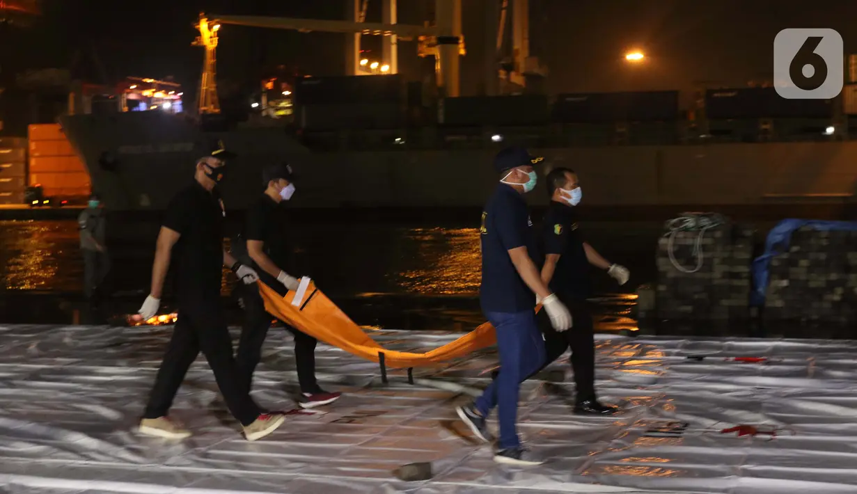 Tim DVI Polri membawa kantong jenazah yang diduga berisi bagian tubuh penumpang pesawat Sriwijaya Air SJ 182 di Dermaga JICT 2, Jakarta, Minggu (10/1/2021) dini hari. Sriwijaya Air SJ 182 membawa 62 penumpang dan kru. (Liputan6.com/Helmi Fithriansyah)